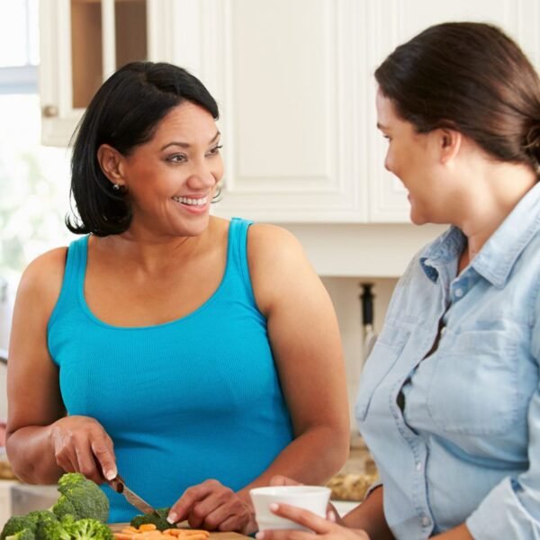 Two women over 40 talking in a kitchen with healthy food