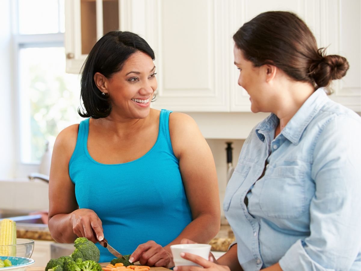 Two women over 40  talking in a kitchen with healthy food